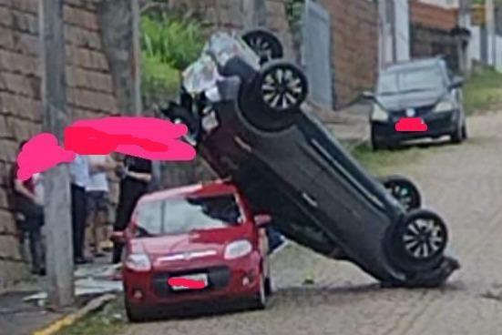 Carro desce da garagem, despenca de muro e fica escorado em outro que estava estacionado
