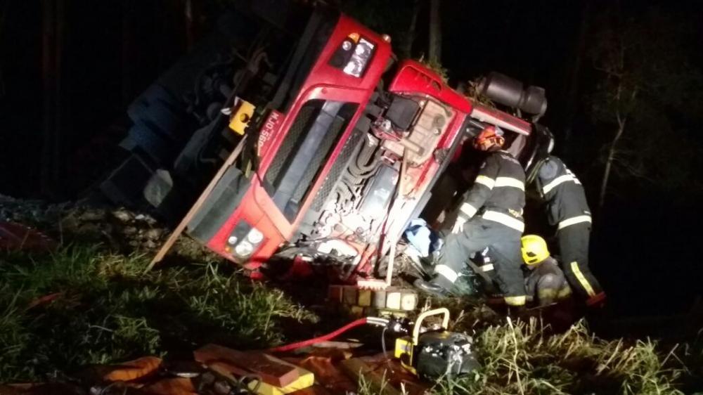 Caminhão carregado com frangos tomba e motorista fica preso às ferragens 